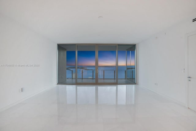 empty room featuring expansive windows and light tile patterned floors