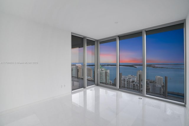 tiled empty room with expansive windows and a water view