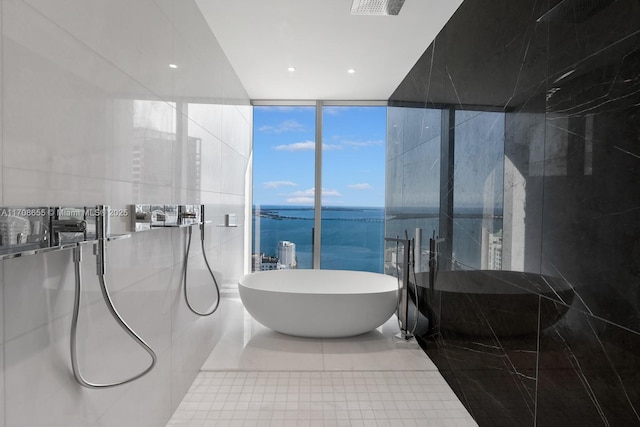 bathroom with a water view, a wall of windows, tile patterned floors, and separate shower and tub