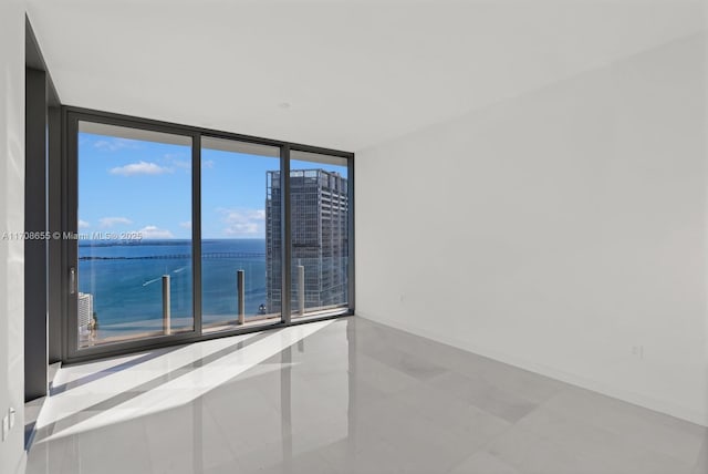 tiled spare room featuring floor to ceiling windows and a water view