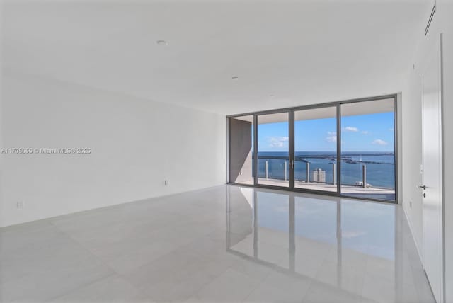 tiled spare room with floor to ceiling windows and a water view