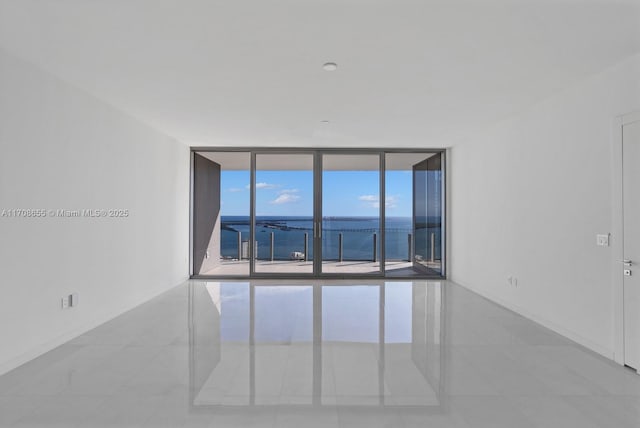 tiled spare room featuring floor to ceiling windows and a water view