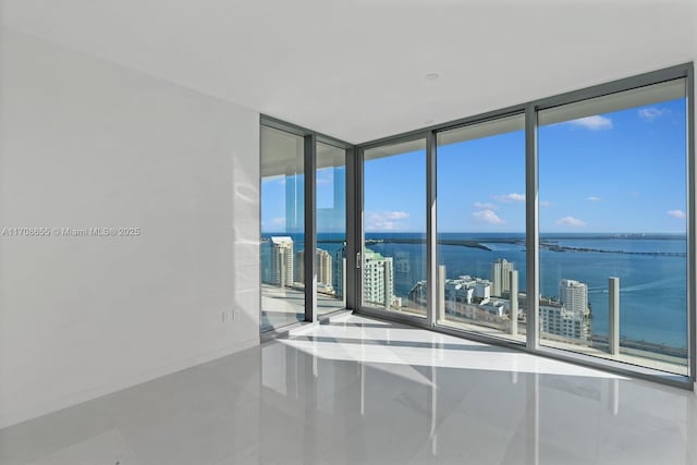 tiled spare room featuring a water view and floor to ceiling windows