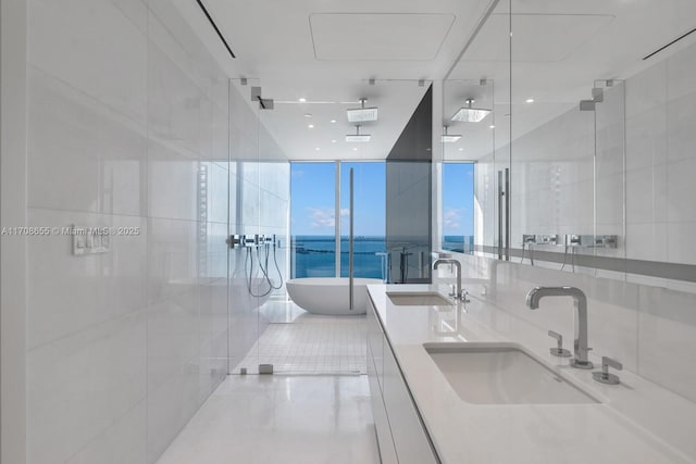 bathroom featuring a wall of windows, tile walls, a water view, vanity, and independent shower and bath