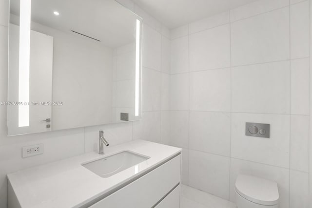 bathroom with vanity, toilet, and tile walls