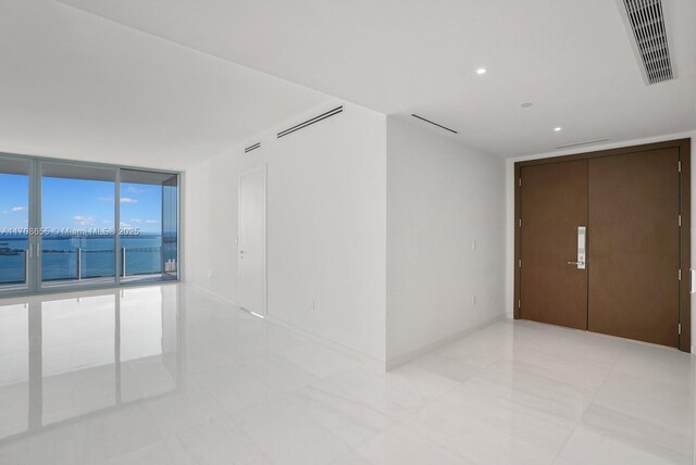 unfurnished room featuring expansive windows and a water view