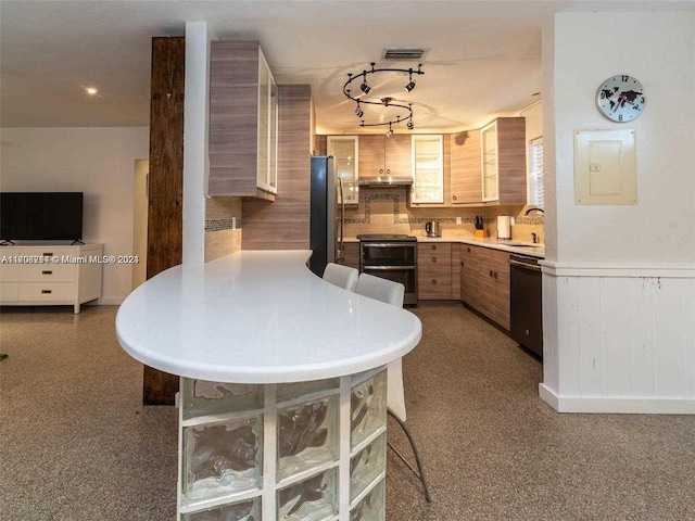 kitchen with electric panel, sink, decorative backsplash, appliances with stainless steel finishes, and a breakfast bar area