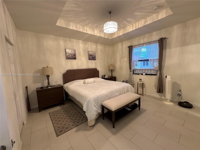 bedroom with light tile patterned floors, a tray ceiling, and a notable chandelier