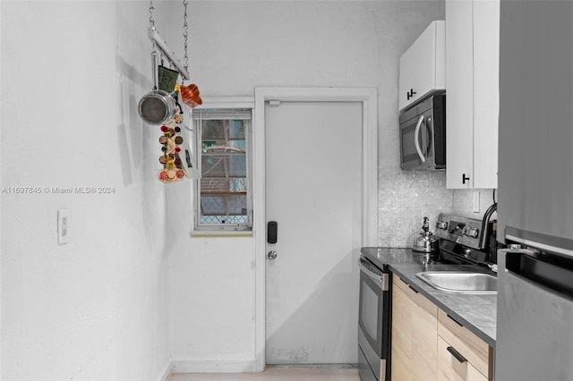 kitchen with appliances with stainless steel finishes, tasteful backsplash, and white cabinetry