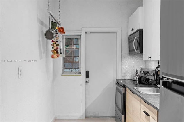 1571 Pennsylvania Ave Unit 4S, Miami Beach, FL 33139 - kitchen featuring appliances with stainless steel finishes, white cabinetry, tasteful backsplash, and dark countertops