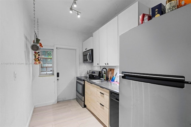 kitchen with tasteful backsplash, stainless steel appliances, sink, light hardwood / wood-style flooring, and white cabinets