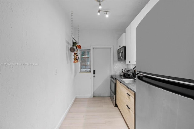 1571 Pennsylvania Ave Unit 4S, Miami Beach, FL 33139 - kitchen with stainless steel appliances, dark countertops, light wood-type flooring, and white cabinetry
