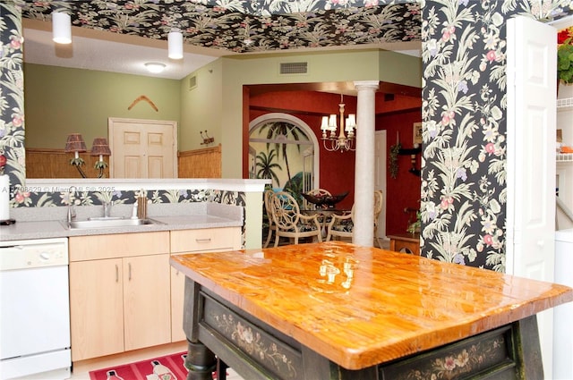 kitchen featuring sink, butcher block counters, white dishwasher, light brown cabinetry, and ornate columns