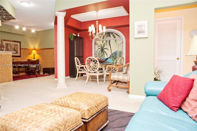 carpeted living room with decorative columns, track lighting, and a chandelier