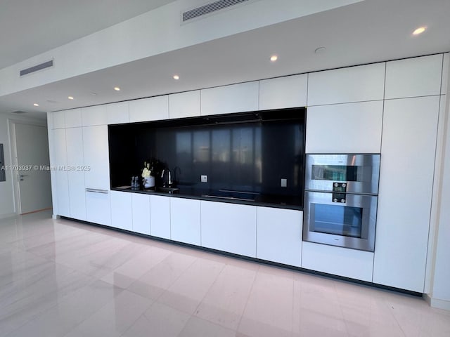 interior space featuring light tile patterned flooring, stainless steel double oven, and white cabinetry