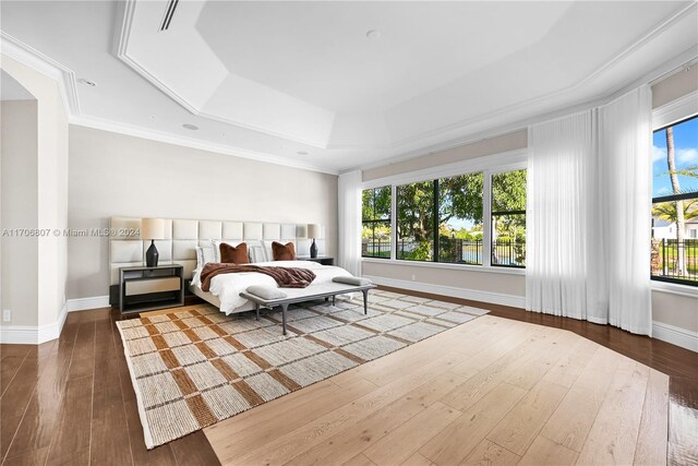 bedroom featuring a raised ceiling, crown molding, and dark hardwood / wood-style flooring