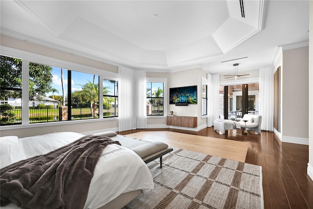 bedroom featuring hardwood / wood-style floors, a raised ceiling, and crown molding