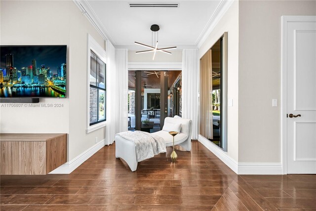 sitting room with a chandelier, dark hardwood / wood-style floors, and ornamental molding