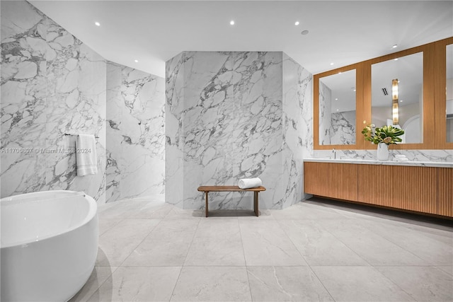 bathroom featuring vanity, a bath, and tile walls