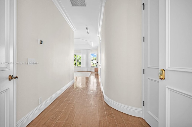 corridor featuring light wood-type flooring and ornamental molding