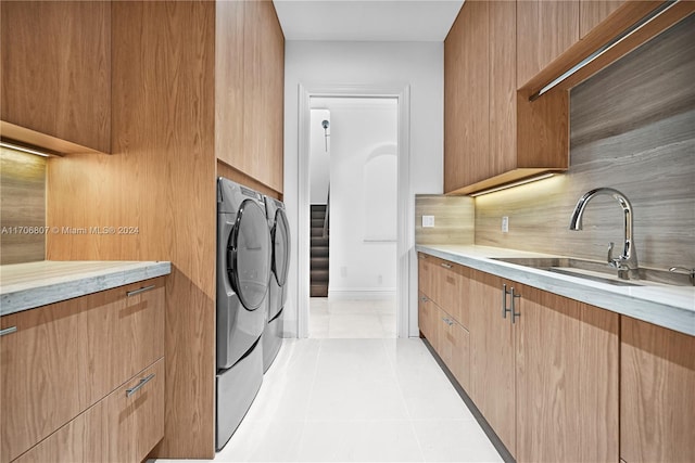 laundry room with washer and dryer, light tile patterned floors, cabinets, and sink