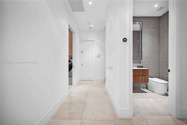 corridor with light tile patterned floors and washer / clothes dryer