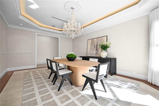 dining area with a raised ceiling, crown molding, light hardwood / wood-style flooring, and a notable chandelier