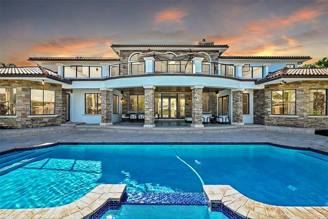 pool at dusk featuring a patio