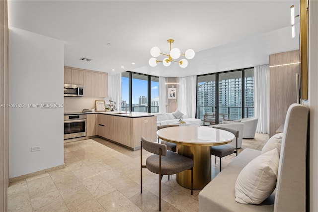 dining room with an inviting chandelier, expansive windows, and sink