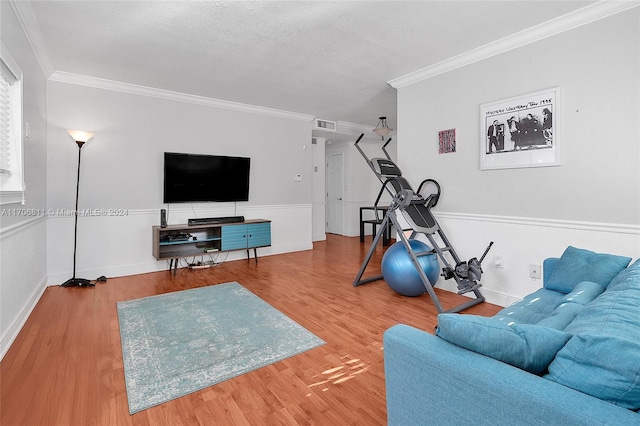 living room featuring wood-type flooring, a textured ceiling, and ornamental molding