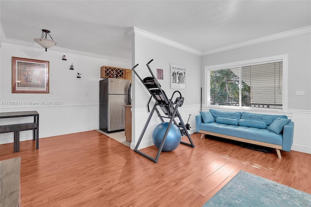 exercise area featuring light hardwood / wood-style flooring, a textured ceiling, and ornamental molding