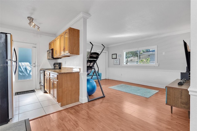 kitchen featuring dark stone counters, stainless steel appliances, crown molding, and light hardwood / wood-style floors