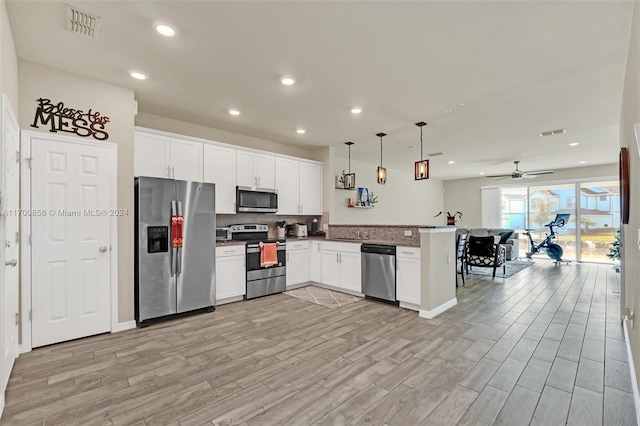 kitchen with pendant lighting, kitchen peninsula, ceiling fan, white cabinetry, and stainless steel appliances