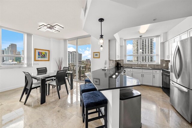 kitchen with a breakfast bar, pendant lighting, stainless steel appliances, and a wealth of natural light