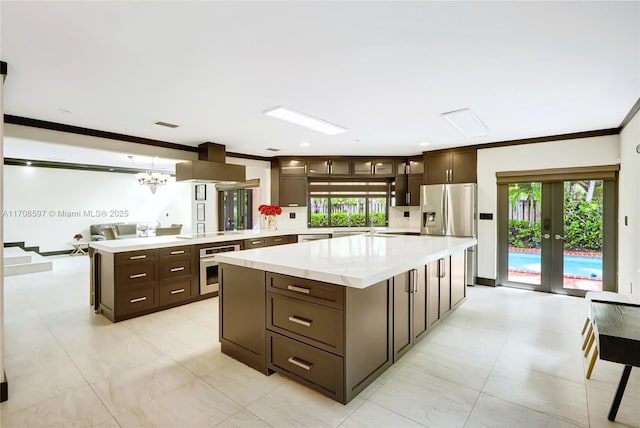 kitchen featuring appliances with stainless steel finishes, sink, island exhaust hood, a center island, and crown molding