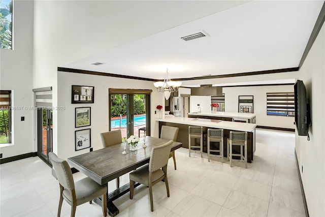 dining area featuring ornamental molding, french doors, and a chandelier