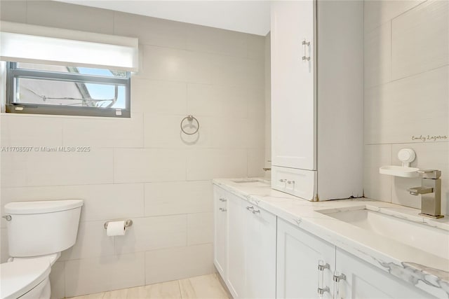 bathroom with vanity, tile walls, and toilet