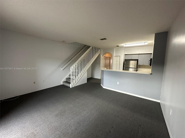 unfurnished living room with carpet flooring and a textured ceiling