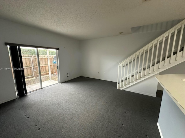 unfurnished living room with dark colored carpet and a textured ceiling