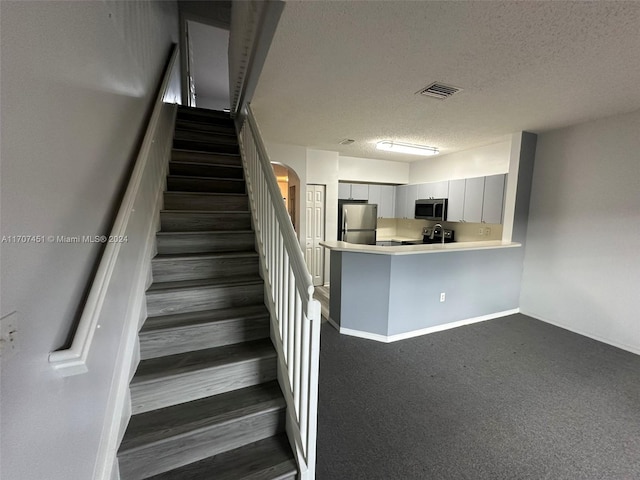 stairway featuring carpet floors and a textured ceiling