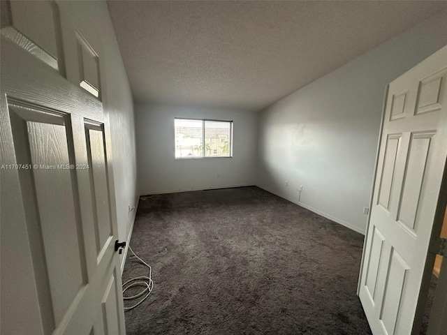 carpeted empty room featuring a textured ceiling