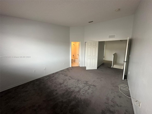 unfurnished bedroom featuring carpet floors, a textured ceiling, and ensuite bath