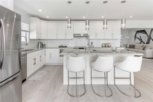 kitchen with appliances with stainless steel finishes, white cabinetry, and decorative light fixtures