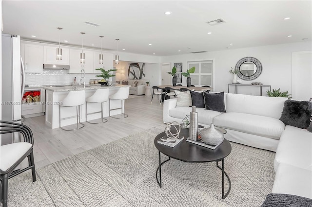 living room with light hardwood / wood-style flooring and sink