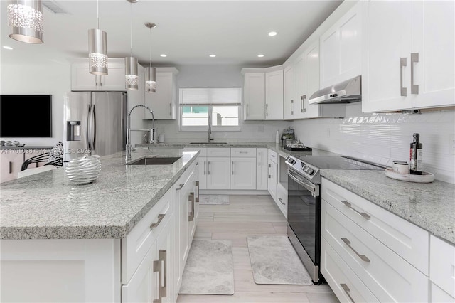 kitchen with appliances with stainless steel finishes, an island with sink, sink, decorative light fixtures, and range hood