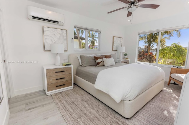 bedroom with ceiling fan, light hardwood / wood-style floors, and an AC wall unit