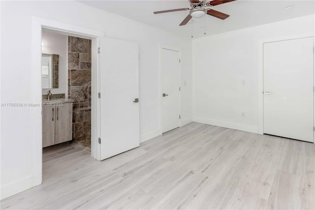 unfurnished bedroom featuring ceiling fan, light wood-type flooring, connected bathroom, and sink