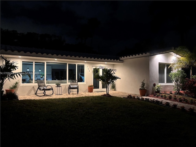 back house at twilight featuring a yard