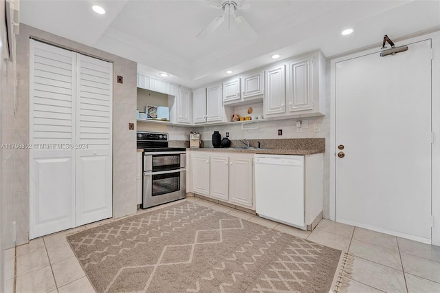 kitchen featuring dishwasher, sink, light tile patterned flooring, stainless steel range with electric stovetop, and white cabinets