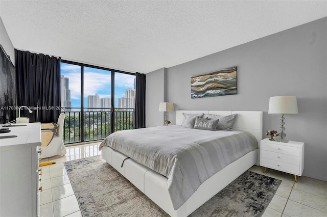 tiled bedroom featuring multiple windows, floor to ceiling windows, a textured ceiling, and access to exterior